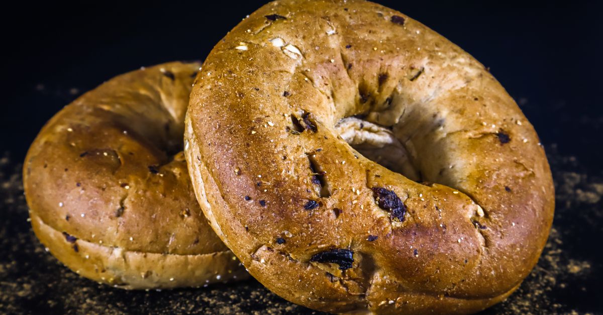 Close-up image of two whole wheat bagels on a dark background, showcasing texture and flavor.